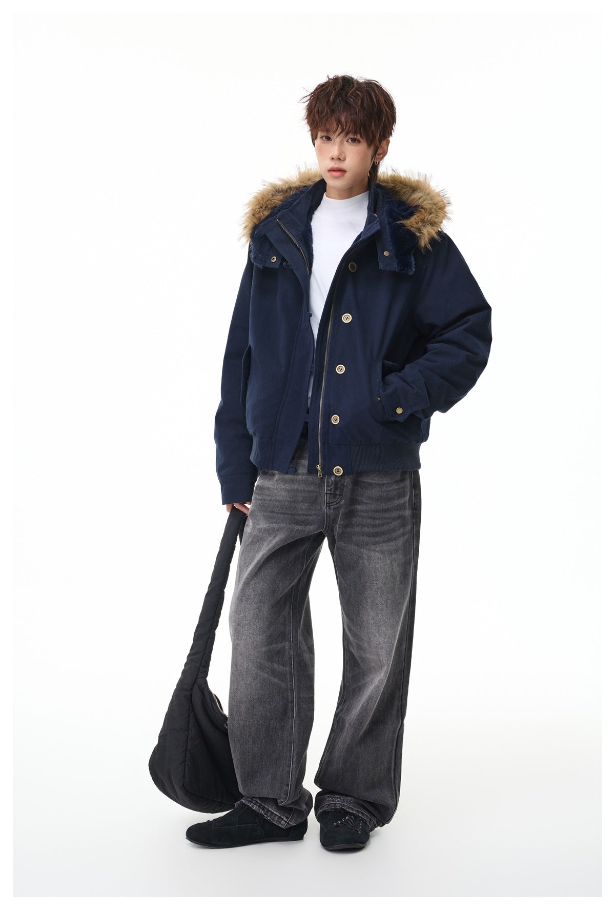 Full-length model wearing a navy fur-trimmed hooded jacket with gray jeans and carrying a black bag.