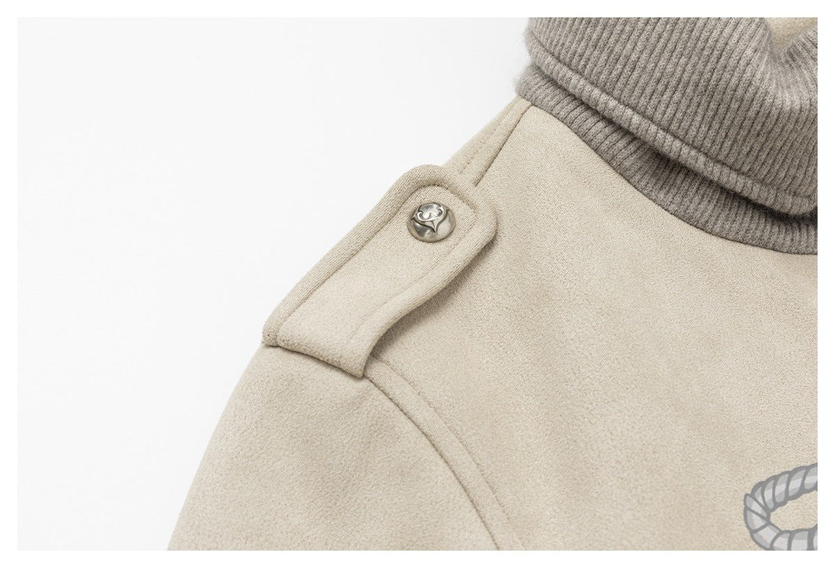 Close-up of a cream shoulder tab with a decorative metal button beside the gray ribbed collar.