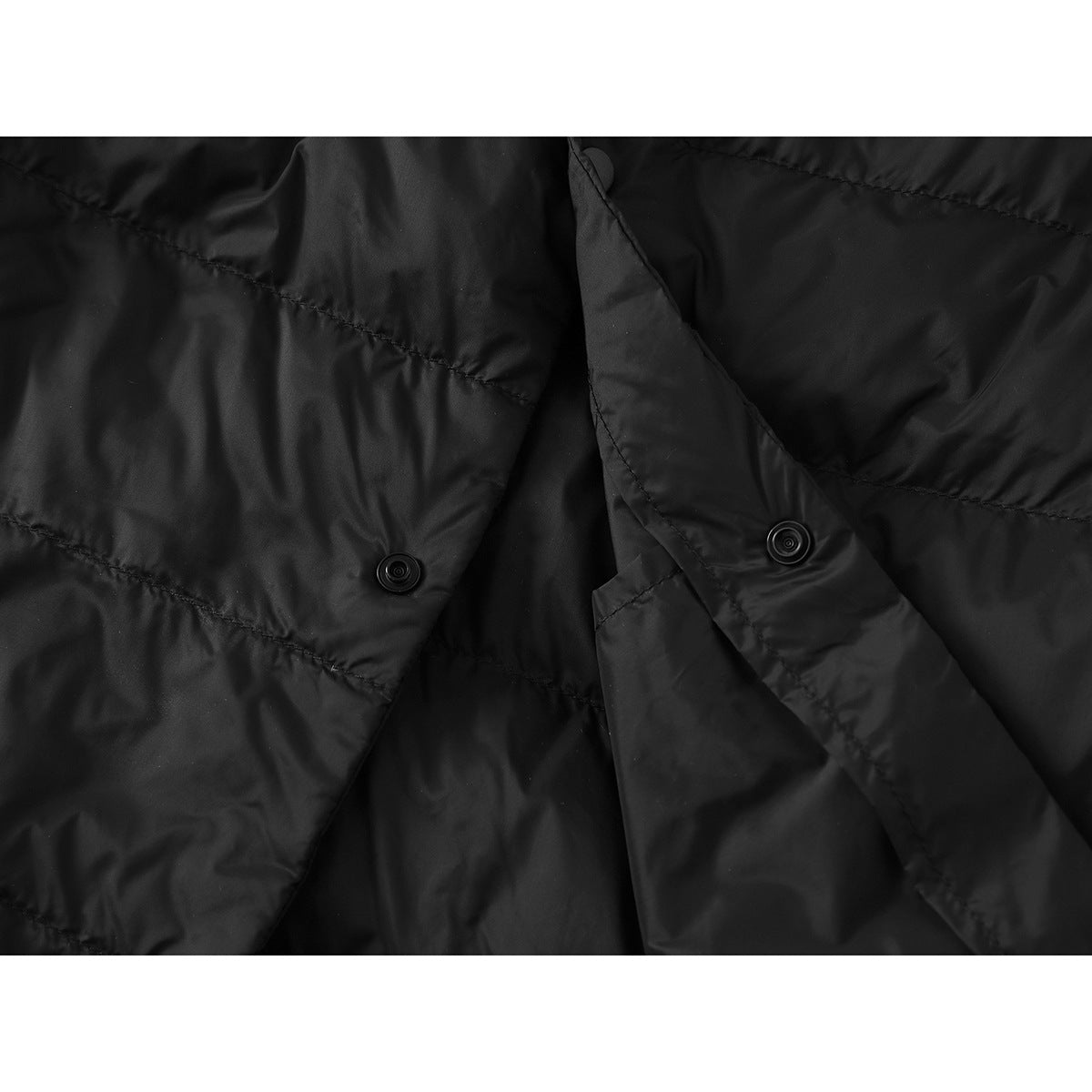 Close-up of the black quilted vest’s open front placket and snap fasteners.