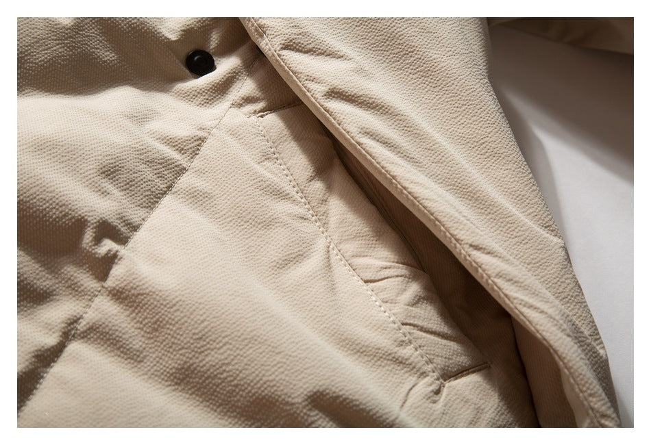 Close-up of a black snap and pocket opening on the textured beige jacket.