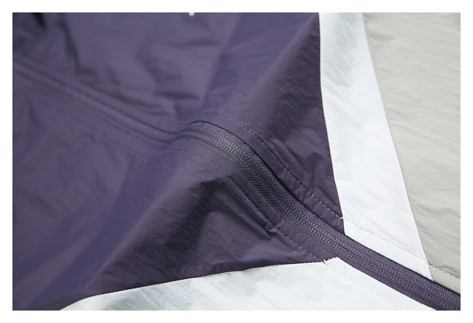 Close-up of the purple zipper and white color-block trim joining light gray windbreaker panels.