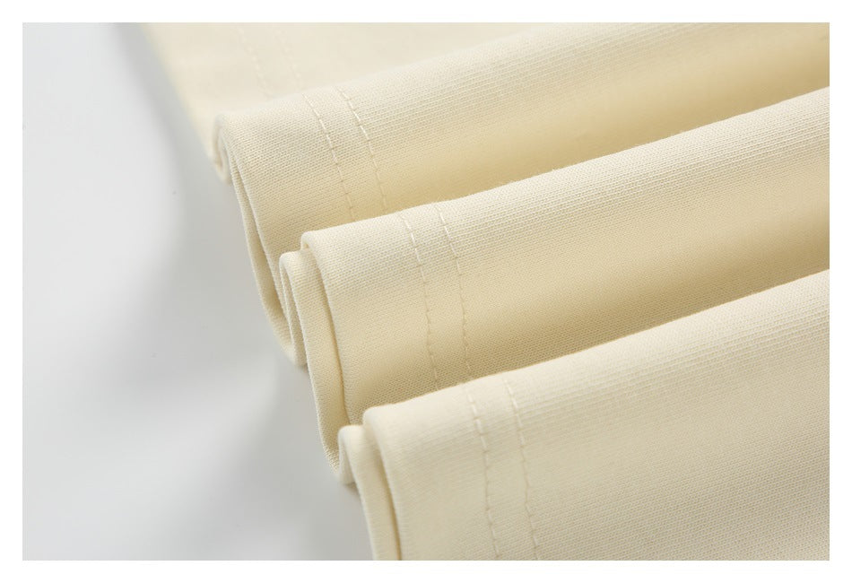 Close-up of folded cream garment edges with double-row stitching.