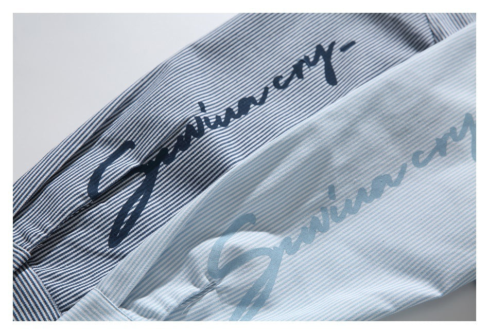 Close-up of blue-and-white striped fabric with dark cursive lettering printed on it.