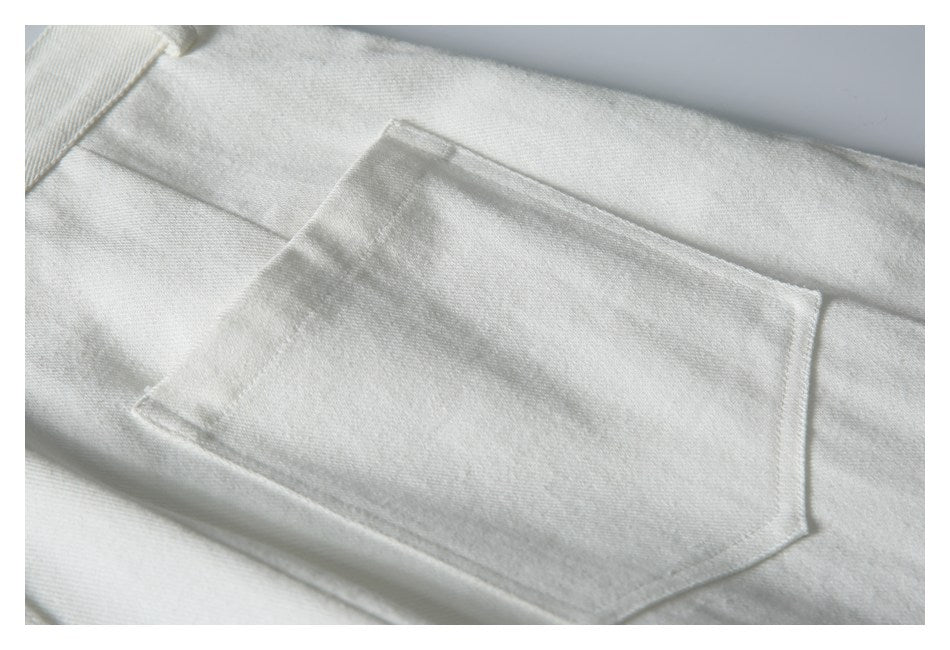 Close-up of a stitched rectangular pocket on white fabric.