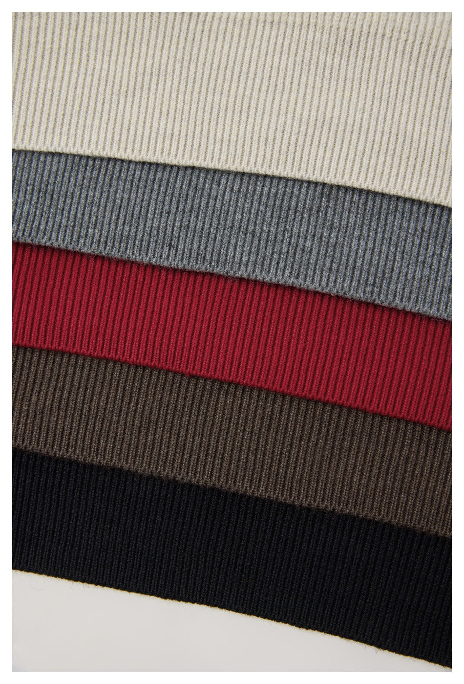Close-up of ribbed knit fabric in cream, gray, red, brown, and black bands.