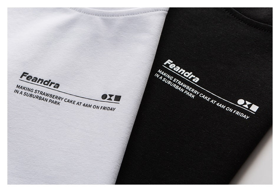 Close-up of white and black T-shirts showing the same printed Feandra text design.