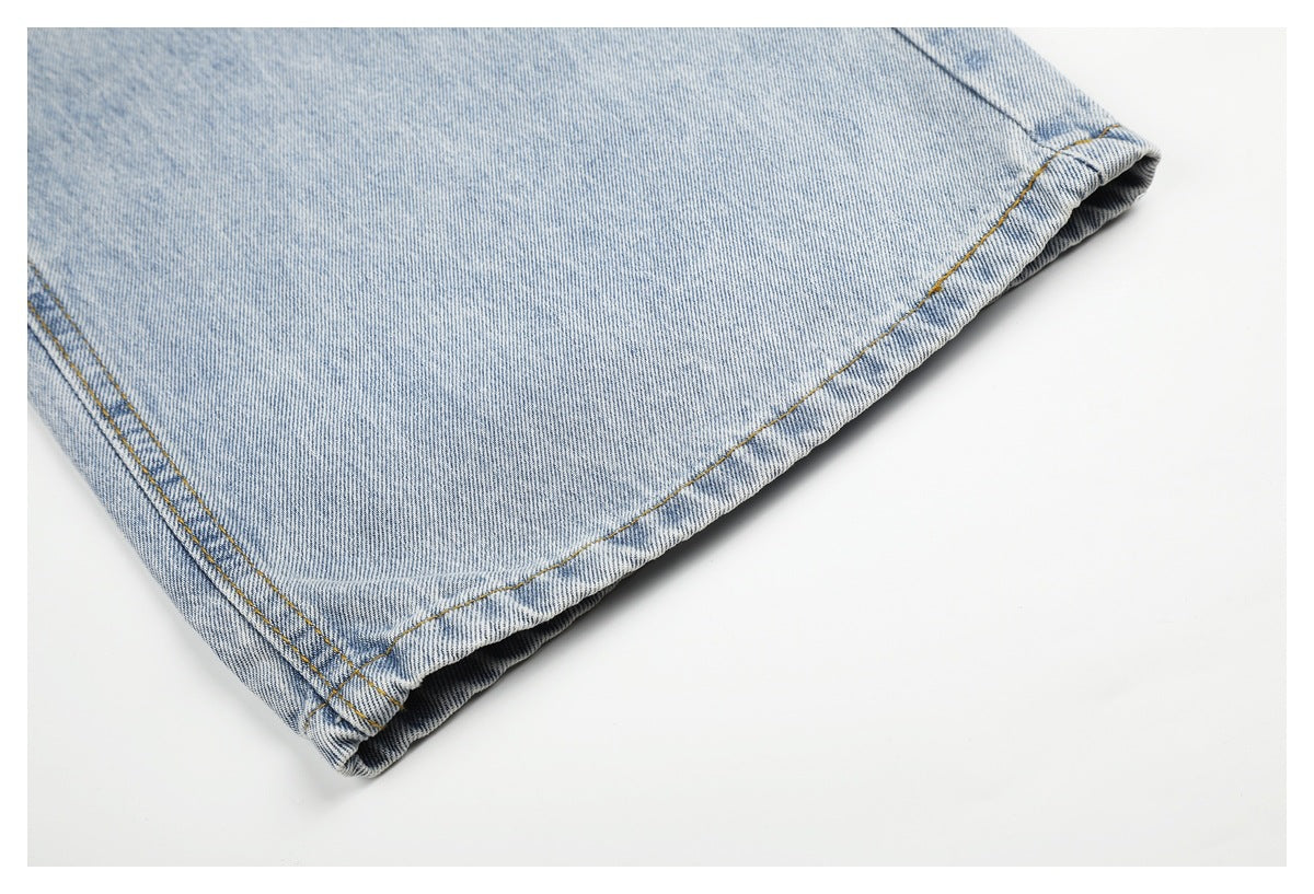 Close-up of the stitched hem of a light blue denim jeans leg laid flat.