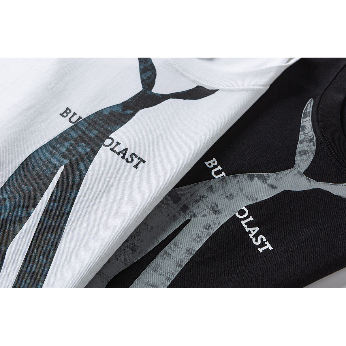 Close-up of white and black T-shirts with large patterned tie graphics and partially obscured English lettering.