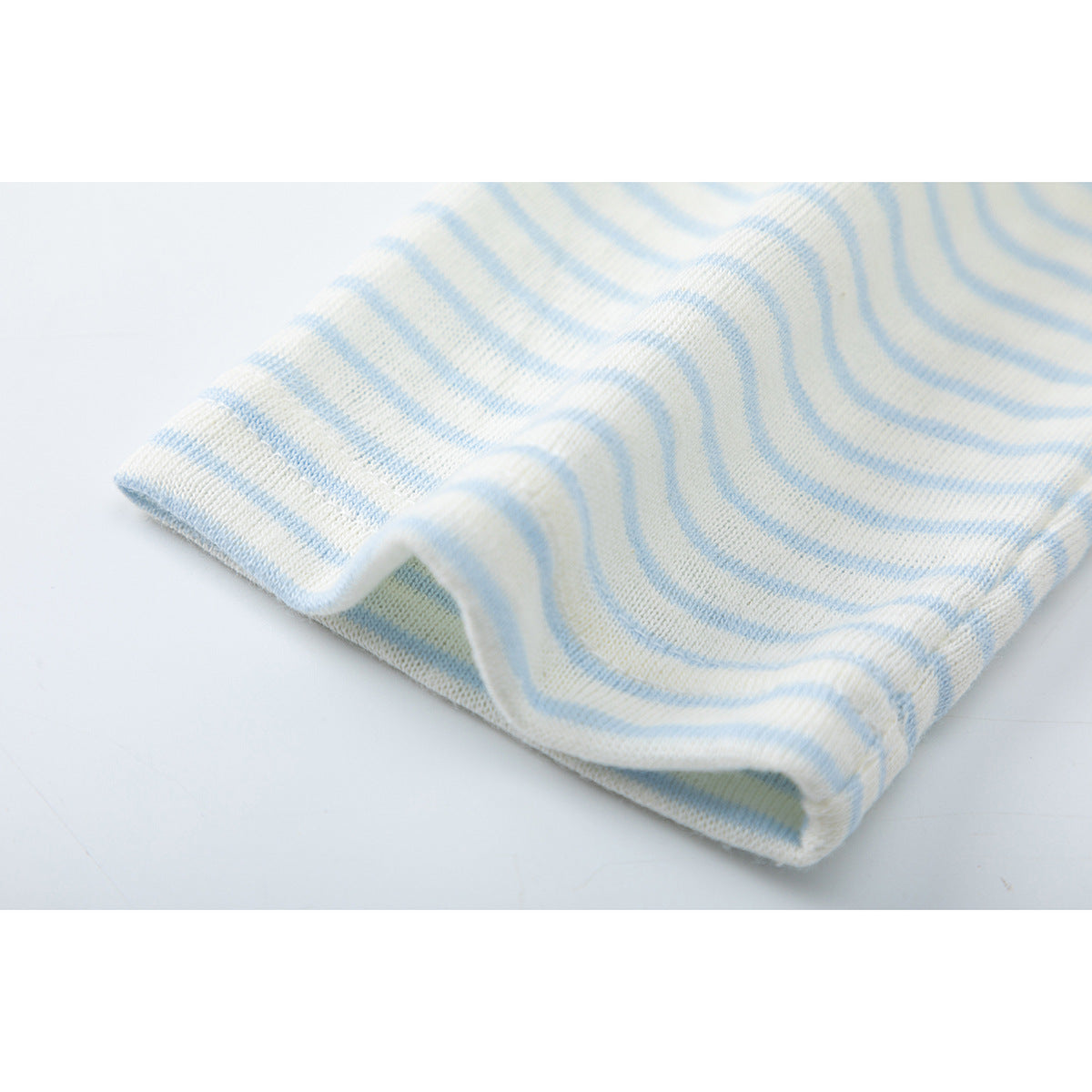 Close-up of a folded edge of cream and pale blue striped fabric.