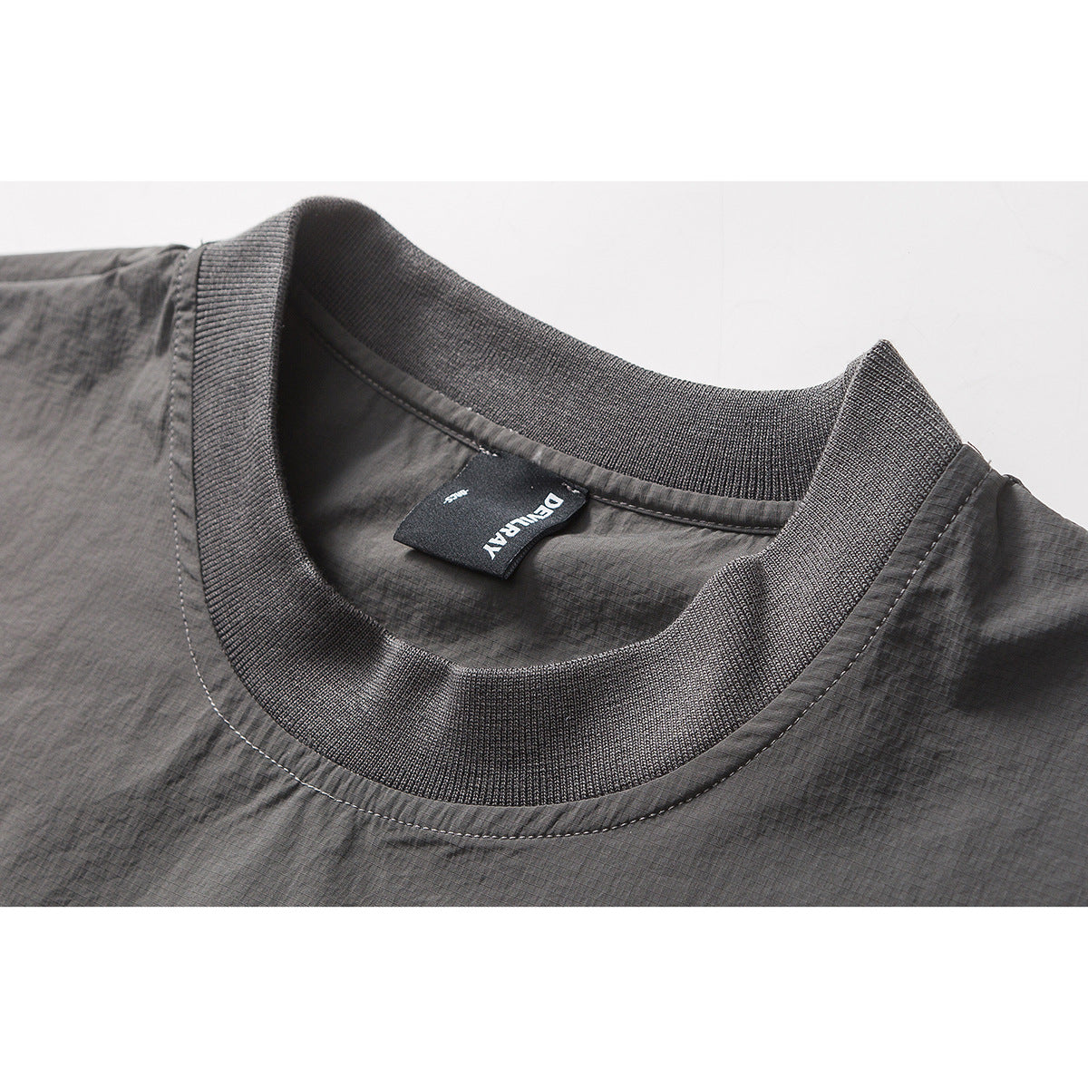 Close-up of a charcoal gray top showing its ribbed crew neck and black inner brand label.