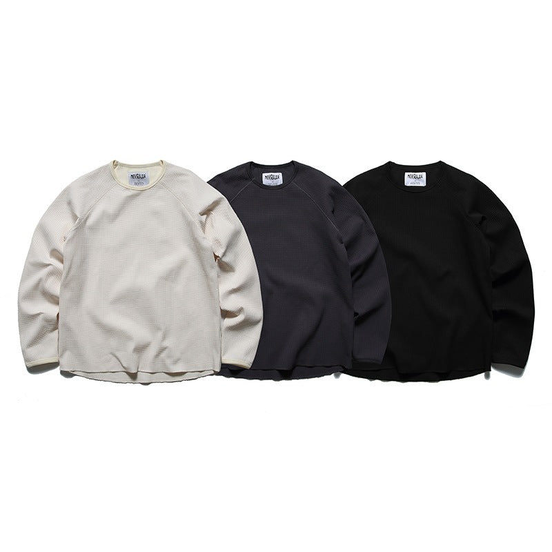 Three long-sleeve waffle-knit crewneck shirts displayed from the front in cream, charcoal, and black.
