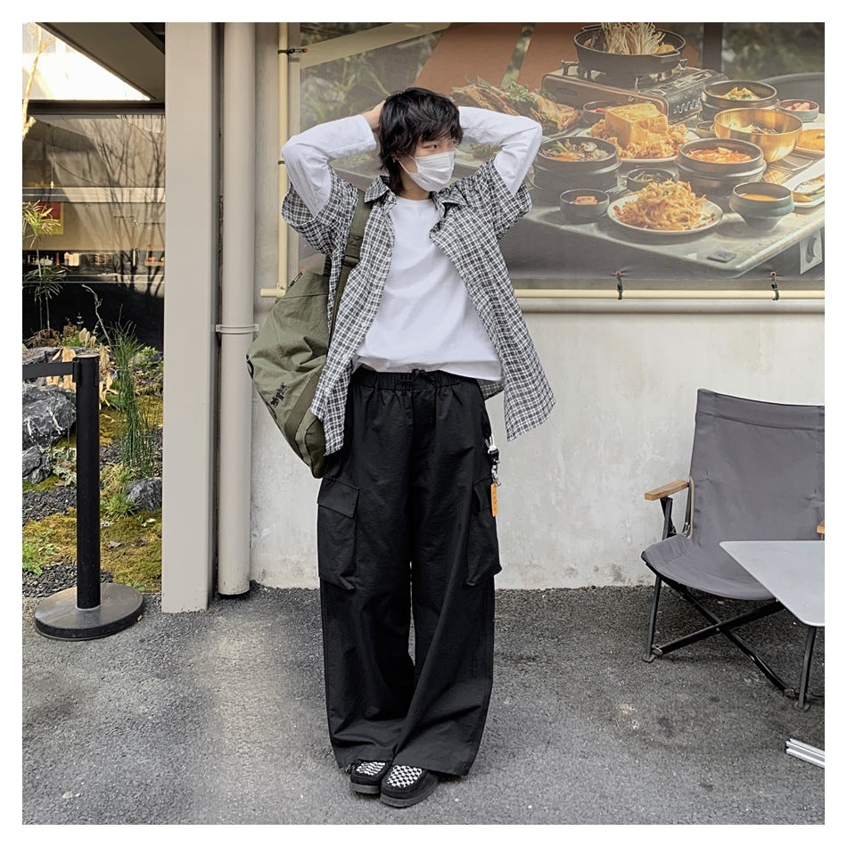 Person wearing black wide-leg cargo pants with an elastic waist and side flap pockets outdoors.