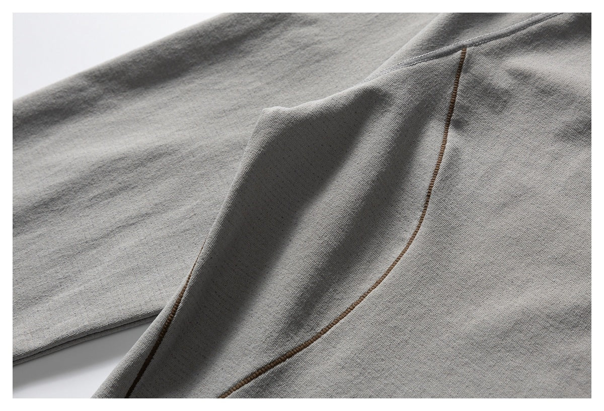 Close-up of a gray garment panel and curved brown contrast stitching.