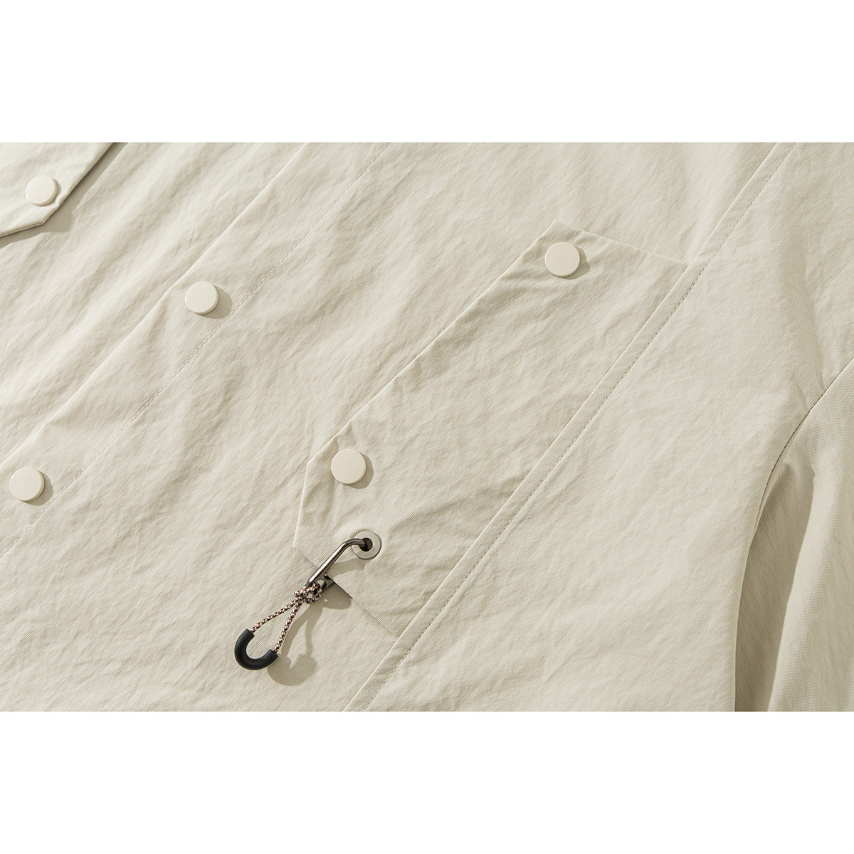 Close-up of the ivory shirt's buttoned front pocket and hook-and-cord accent.