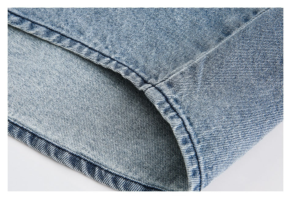 Close-up of a folded light blue denim garment showing an interior seam and stitching.