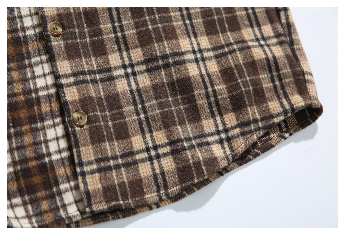 Close-up of the brown plaid shirt's curved hem and two tan front buttons.