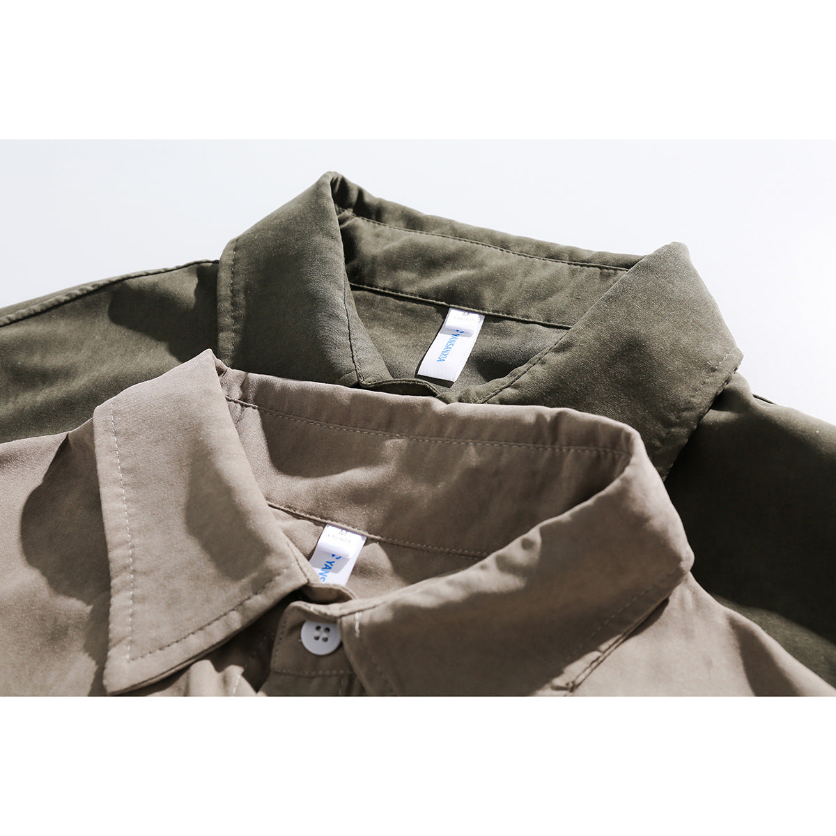 Close-up of overlapping taupe and olive button-up shirt collars with visible stitching and neck labels.