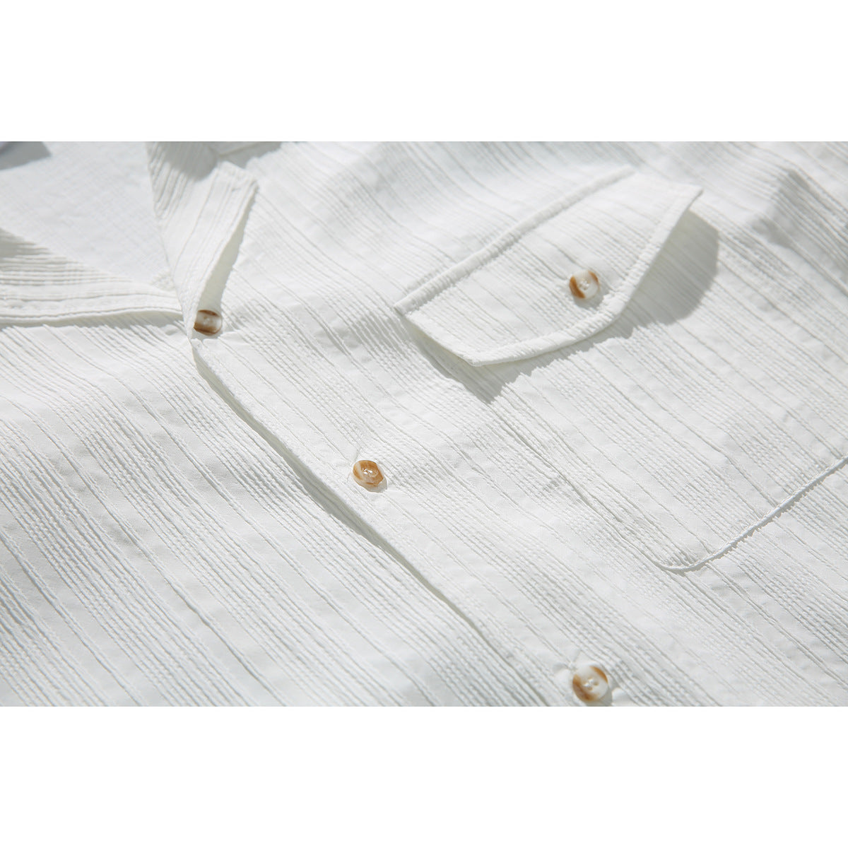 Close-up of the white shirt's textured striped fabric, tan buttons, and flap chest pocket.