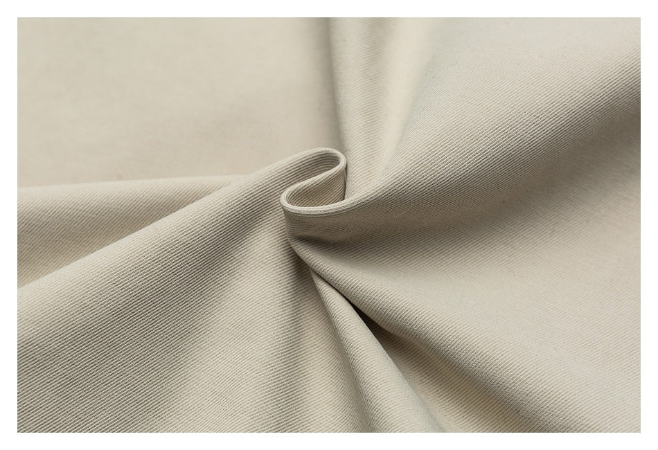 Close-up of beige fabric draped into soft folds, showing its fine diagonal weave.