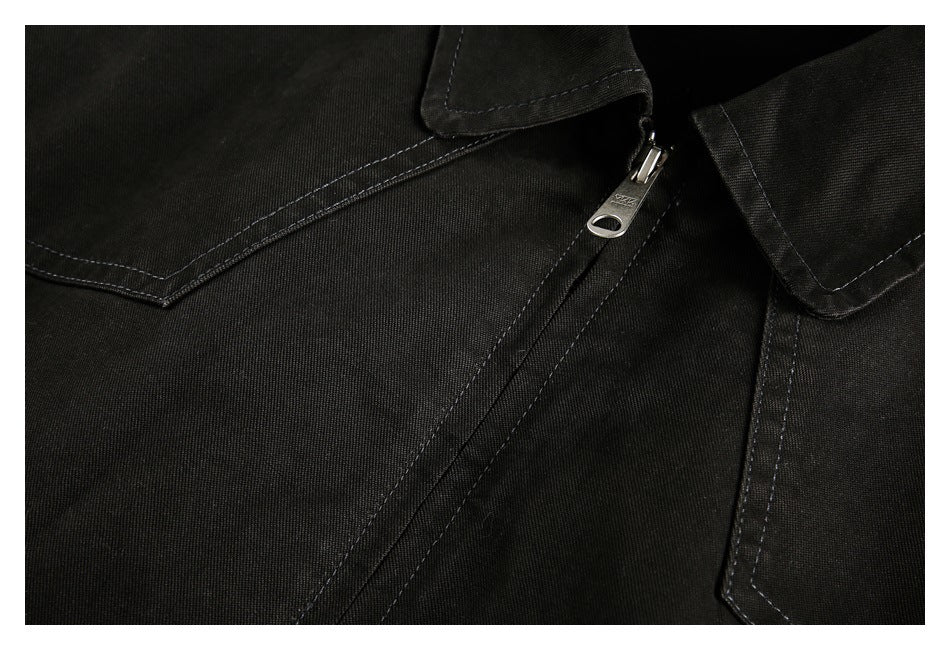 Close-up of the black jacket's metal zipper pull and double-stitched front panel seams.