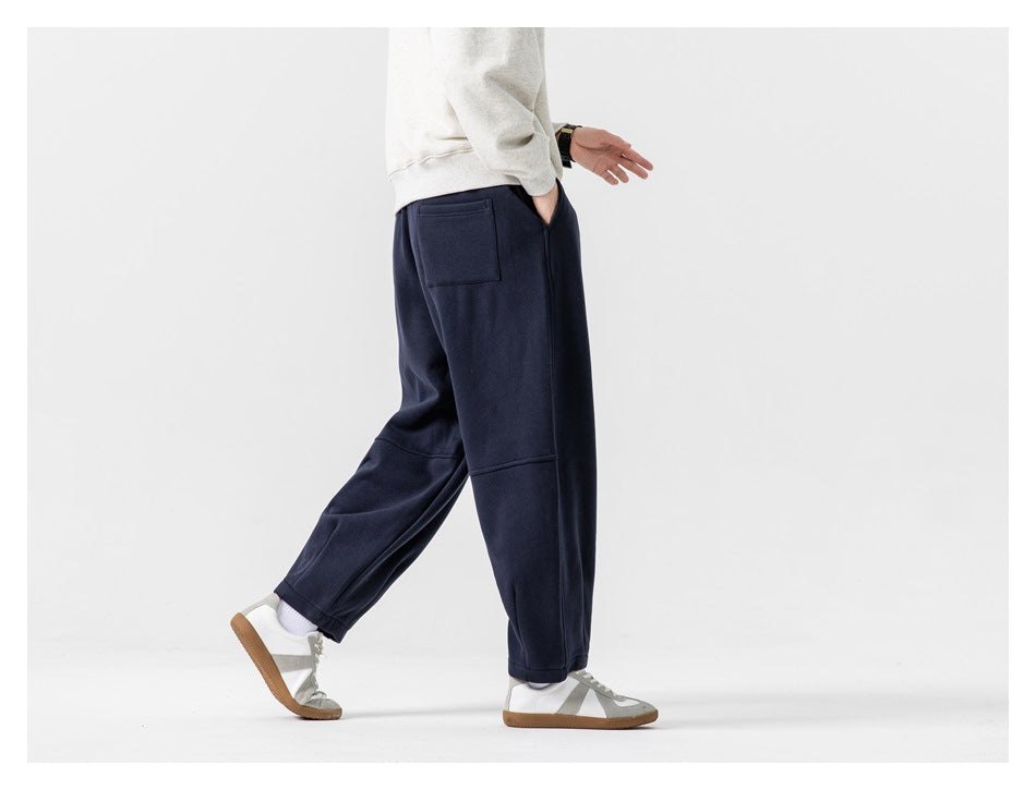 Rear three-quarter view of a model wearing navy joggers, showing the back patch pocket and relaxed fit.