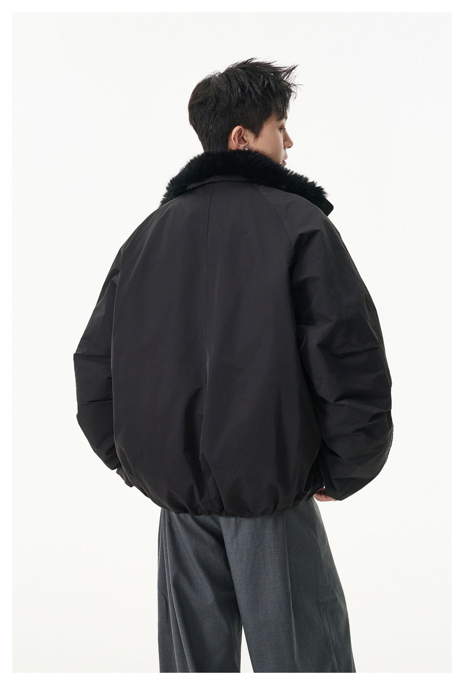 Rear view of a model wearing a black oversized jacket with a black plush collar.