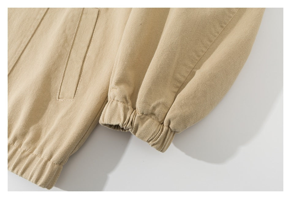 Close-up of a beige garment's elastic cuff and nearby welt pocket.