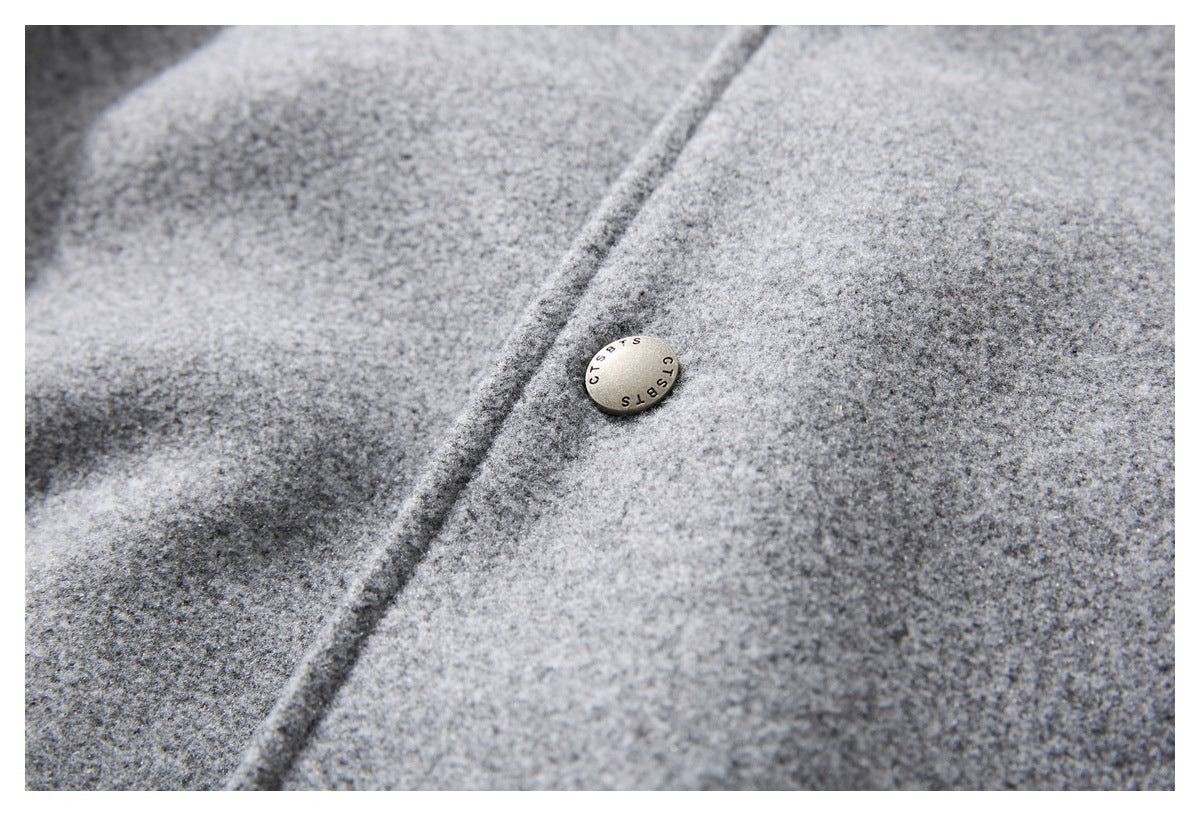 Close-up of a metal button on the textured gray jacket fabric.