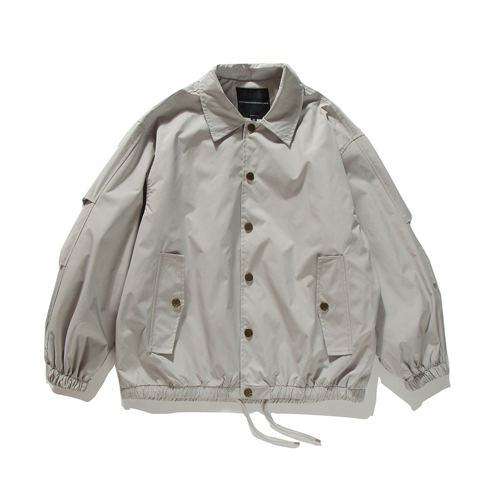 Beige coach-style jacket flat lay, front view with gold buttons, flap pockets, elastic cuffs and drawstring hem