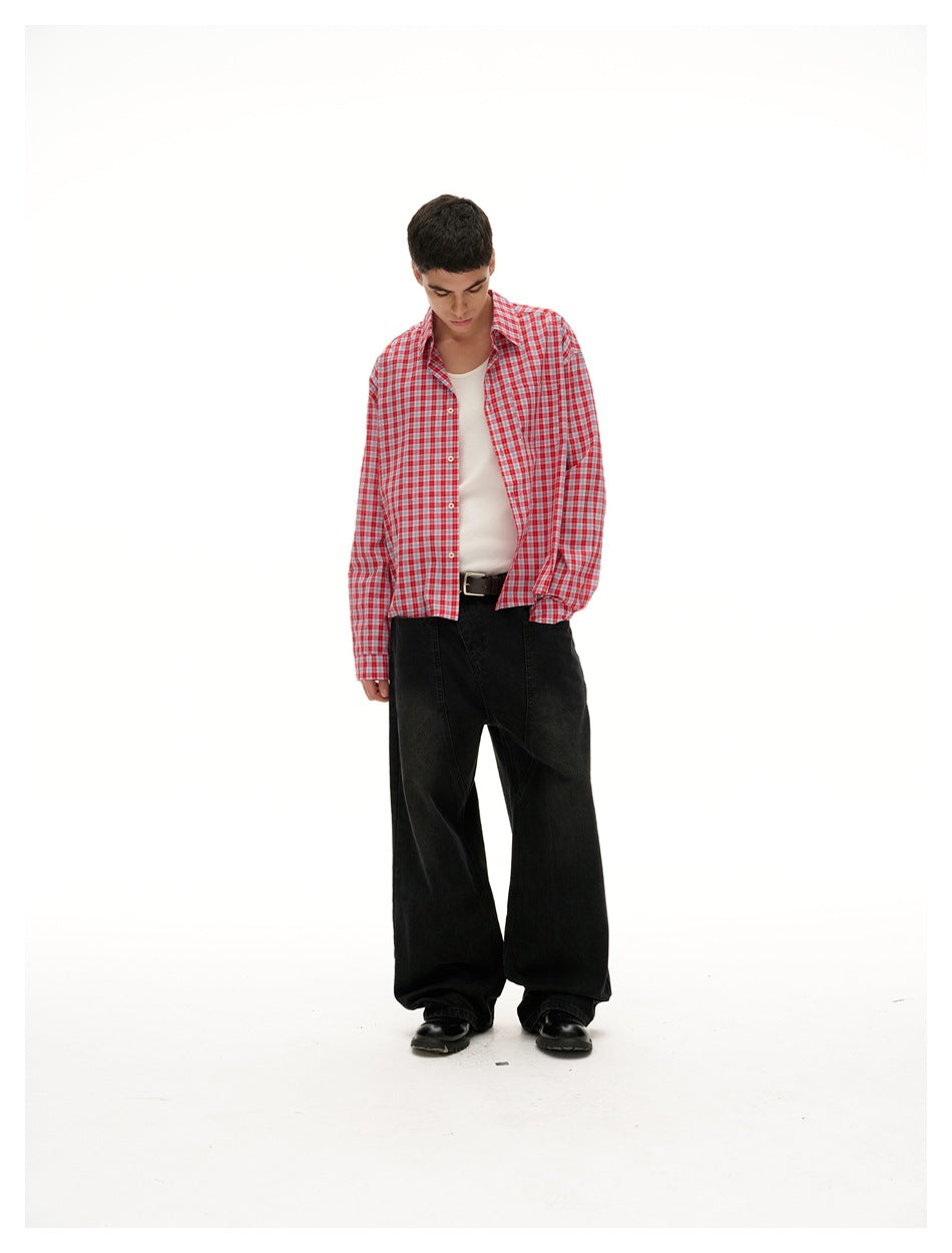 Model looking down in an open red-and-white plaid shirt, white top, and black wide-leg trousers.