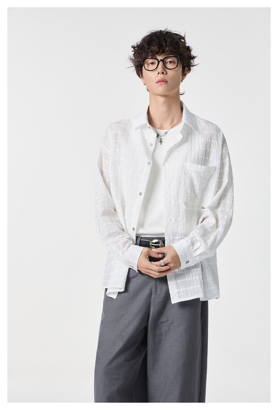 Model wearing a white textured button-up shirt over a white tee with gray wide-leg trousers.