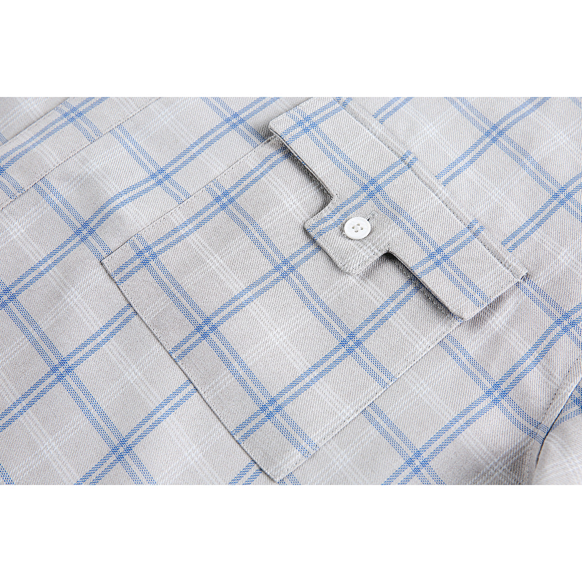 Close-up of a buttoned chest pocket on a gray shirt with a blue plaid pattern.
