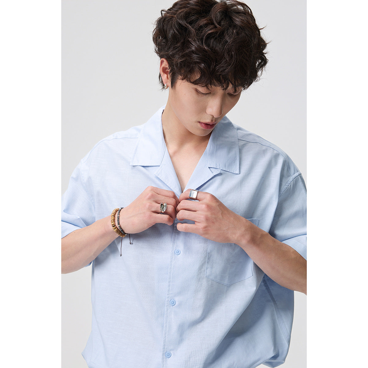 Close view of a model wearing a light blue short-sleeve button-up shirt with a notched collar and chest pocket.