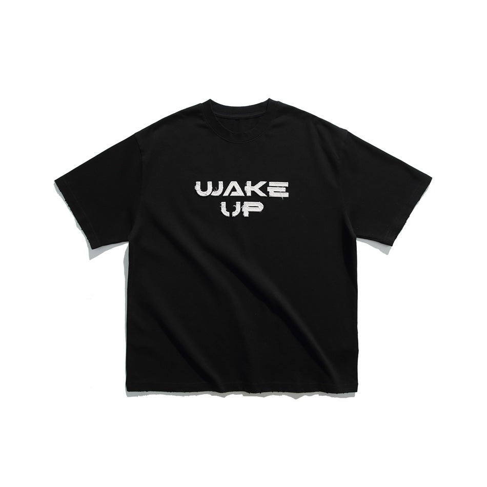 Black short-sleeve crew-neck T-shirt with white frayed WAKE UP appliqué lettering, flat lay