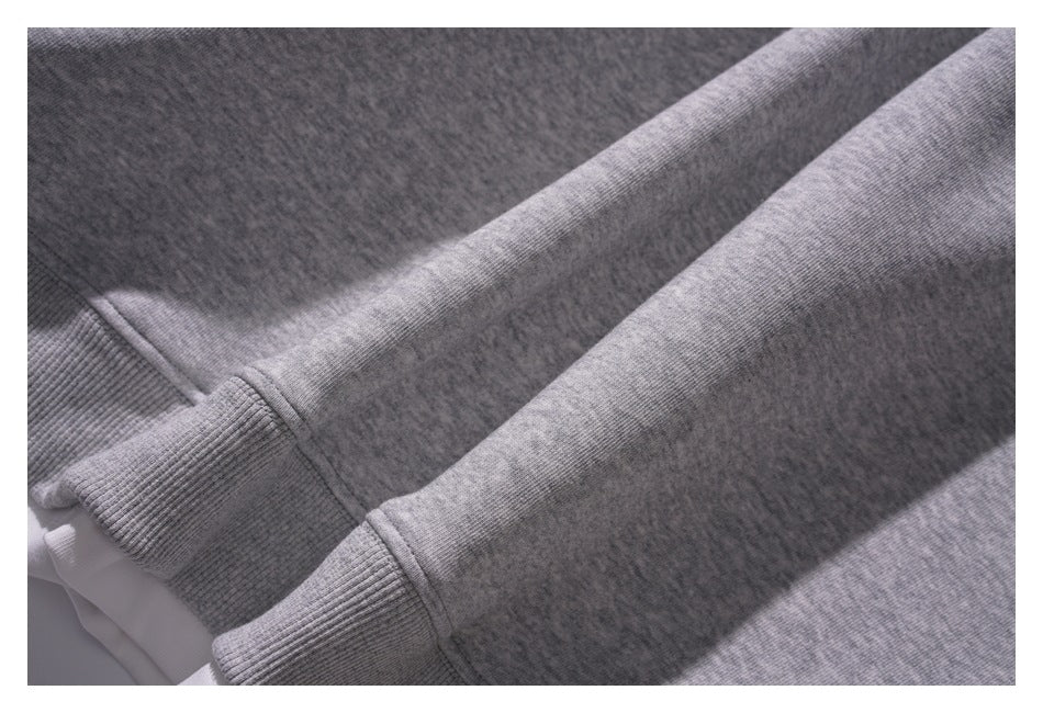 Close-up of a heather gray garment with long sleeves and ribbed cuffs, showing seams and knit texture.