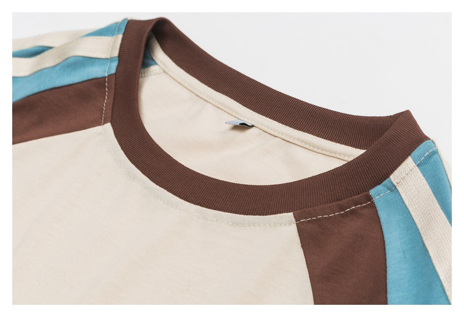 Close-up of a cream shirt's brown ribbed crew neck and blue and brown shoulder panels.