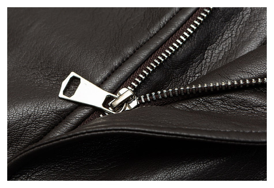 Close-up of a shiny metal zipper and pull on dark, pebbled leather-like material.