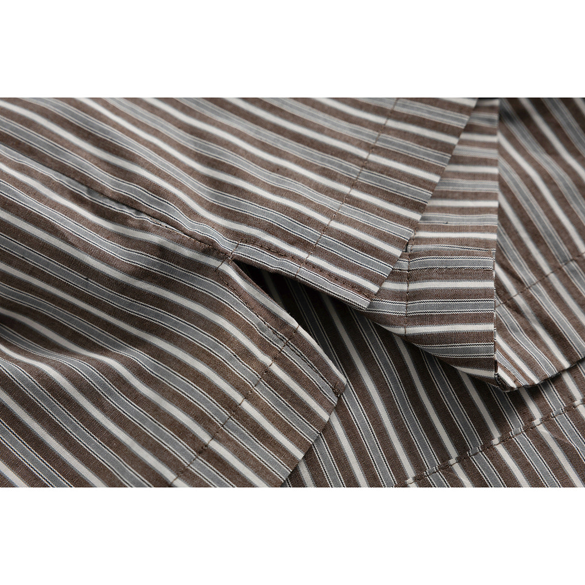 Close-up of the striped shirt's collar edge, fabric and stitching in brown, gray and white.