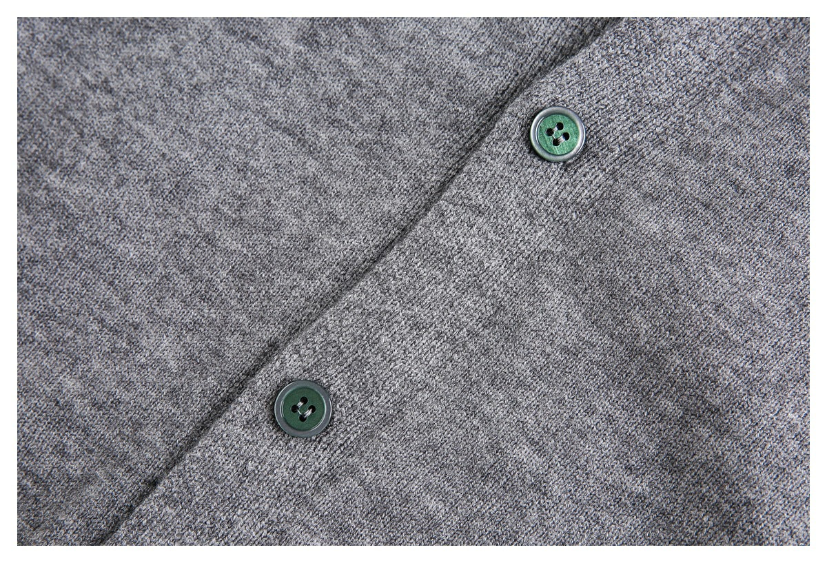 Close-up of a heather gray knit cardigan placket with two dark green buttons.