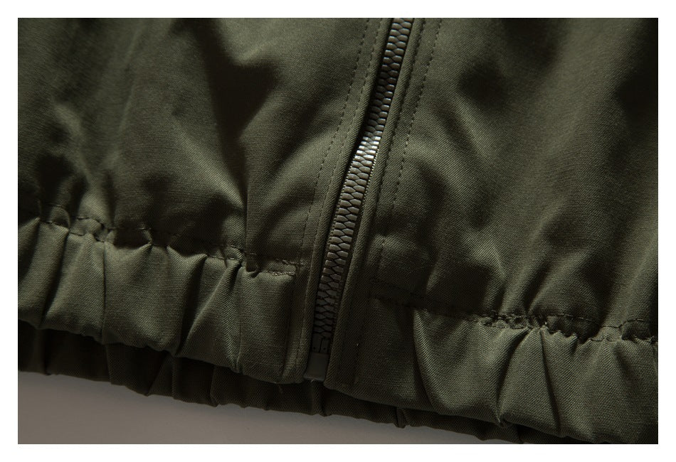 Close-up of an olive jacket's zipper and gathered elastic hem.