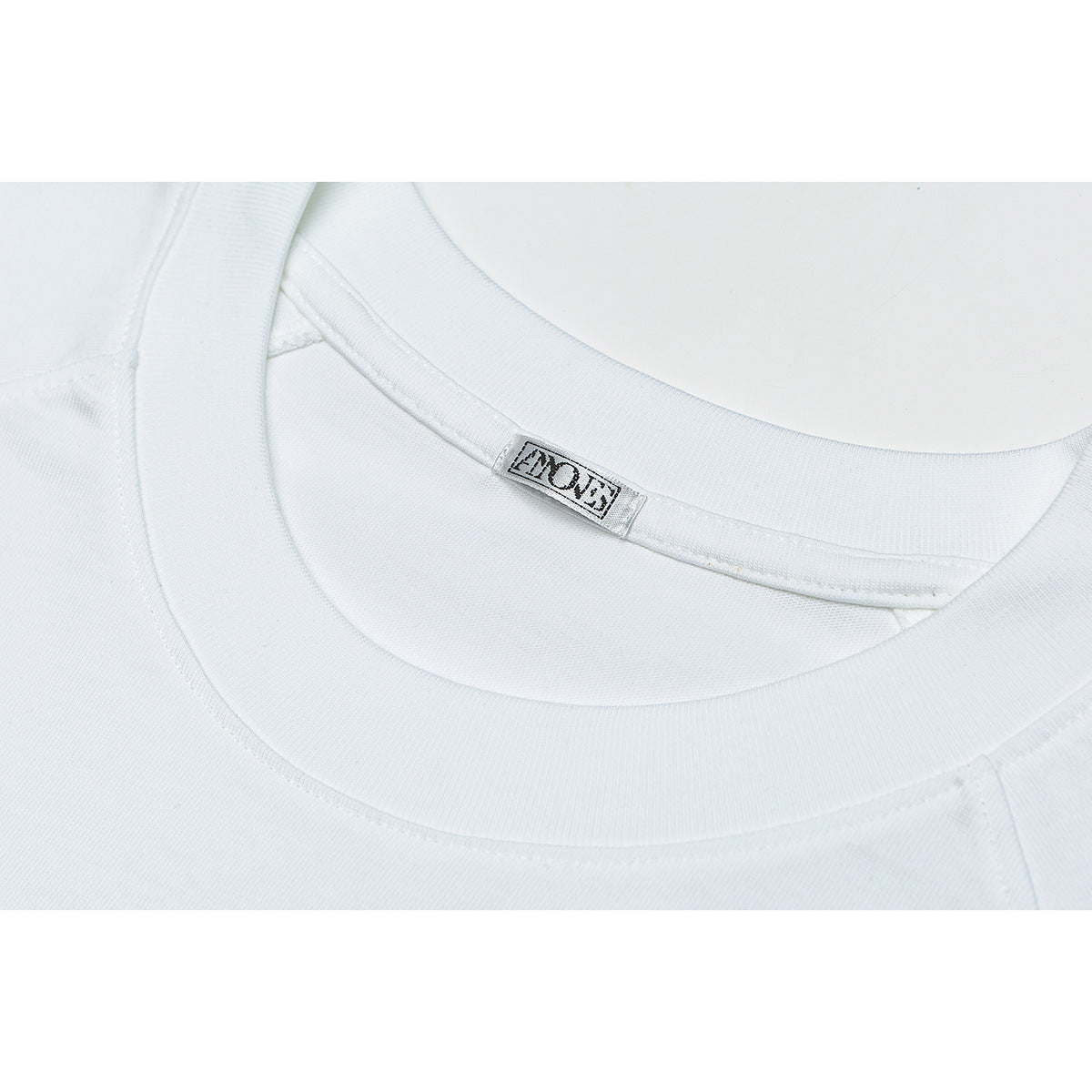 Close-up of the white T-shirt’s crew neckline and sewn-in neck label.