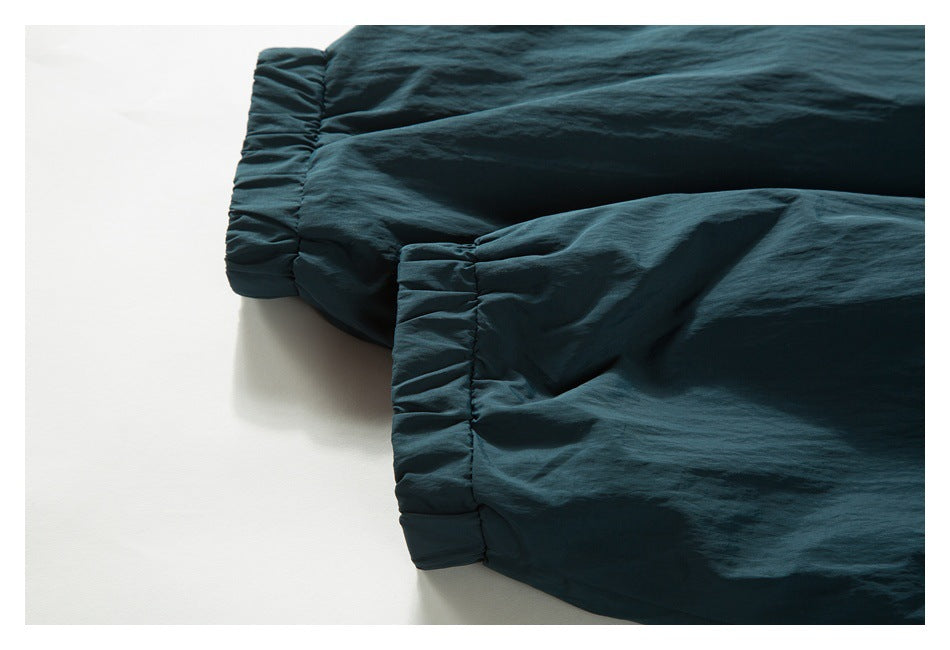 Close-up of two gathered cuffs on a dark teal garment.