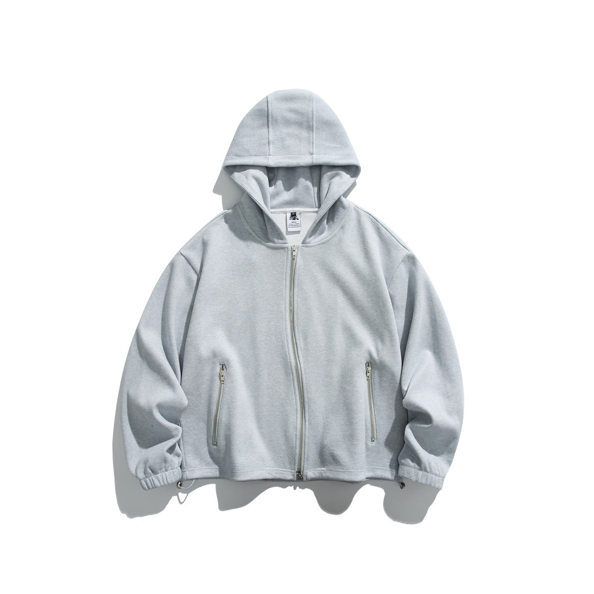 Heathered light blue zip-front hoodie flat lay with paneled hood, zippered pockets, elastic cuffs and hem toggles