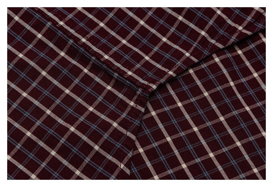 Close-up of intersecting seams on burgundy fabric with a cream and blue plaid pattern.