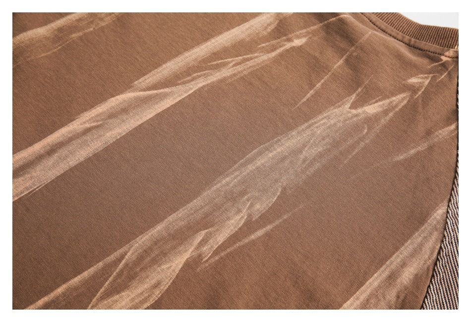 Close-up of a brown garment with pale distressed streaks and a ribbed crew neckline.