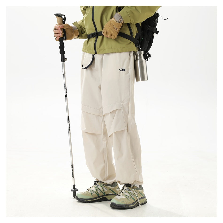 Three-quarter view of a model wearing loose ivory trousers with layered knee panels and a small dark emblem.