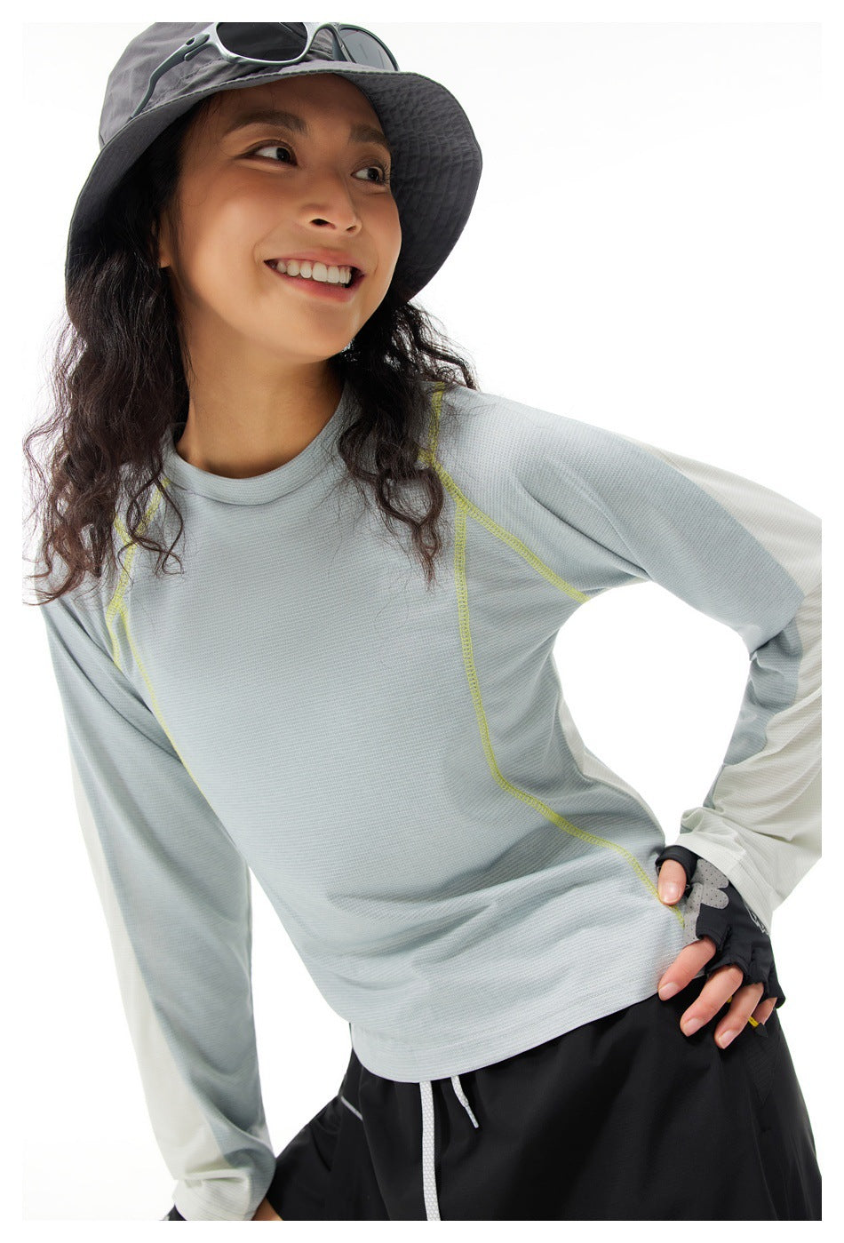 Close view of a model wearing a pale gray long-sleeve top with contrasting white sleeves and lime stitching.