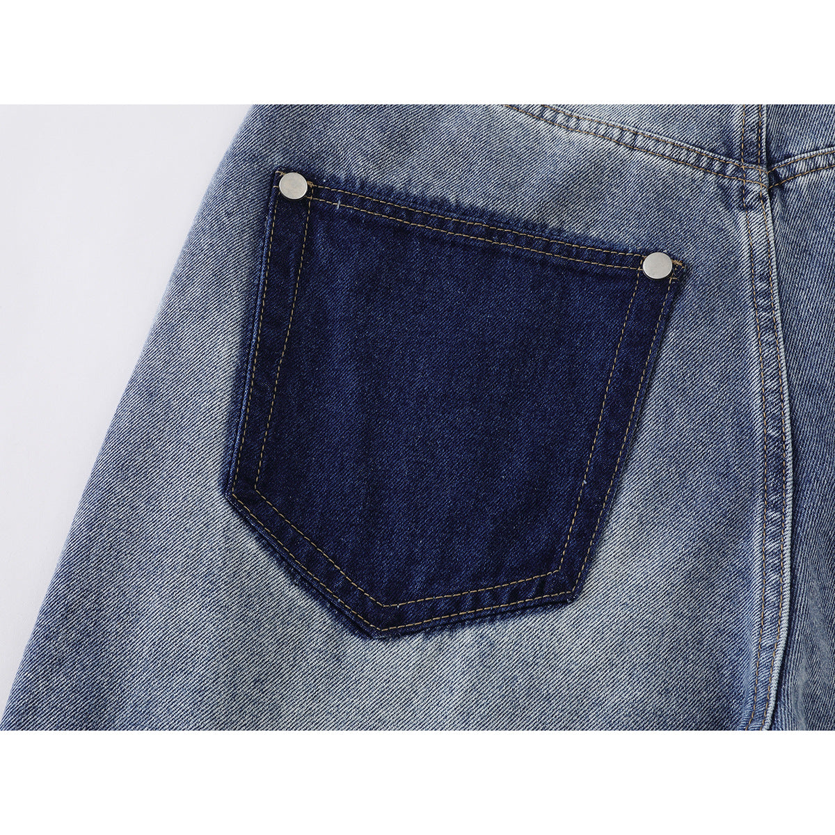 Close-up of a dark contrast back pocket with metal rivets on faded blue jeans.