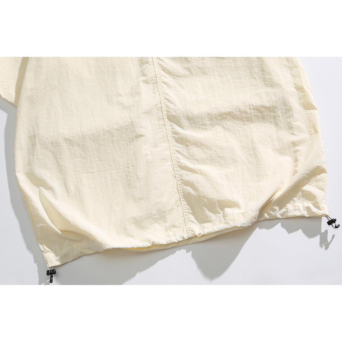 Close view of the ivory shirt's back hem with adjustable drawcords at the sides.
