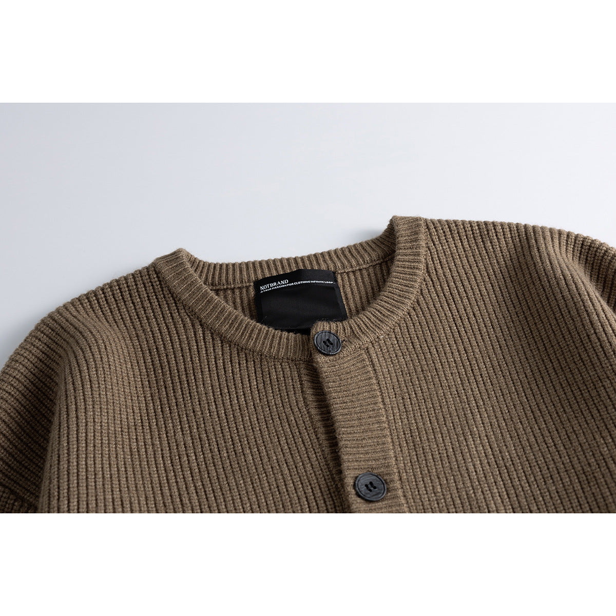 Close-up of a taupe-brown ribbed cardigan neckline, dark buttons and sewn black neck label.